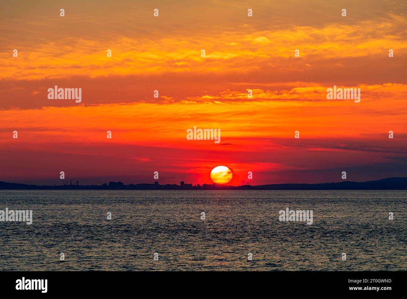 Il sole che tramonta illumina la nuvola lungo la costa gallese Foto Stock