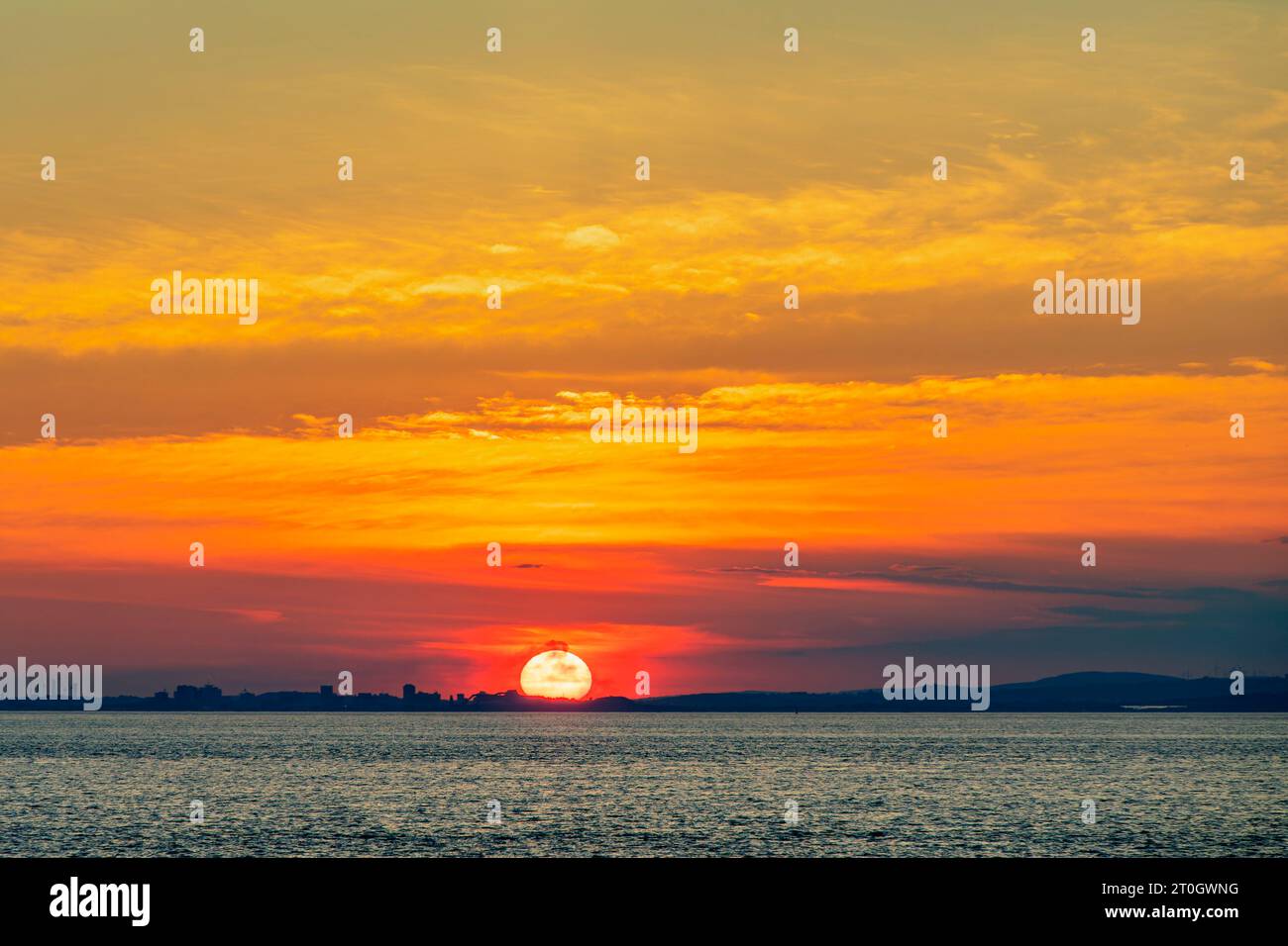 Il sole che tramonta illumina la nuvola lungo la costa gallese Foto Stock