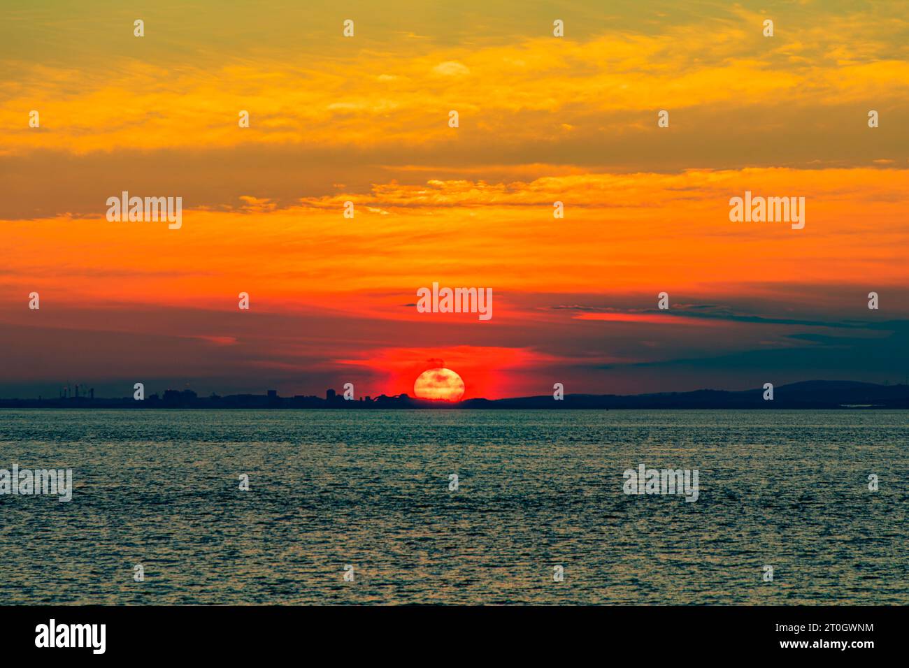 Il sole che tramonta illumina la nuvola lungo la costa gallese Foto Stock