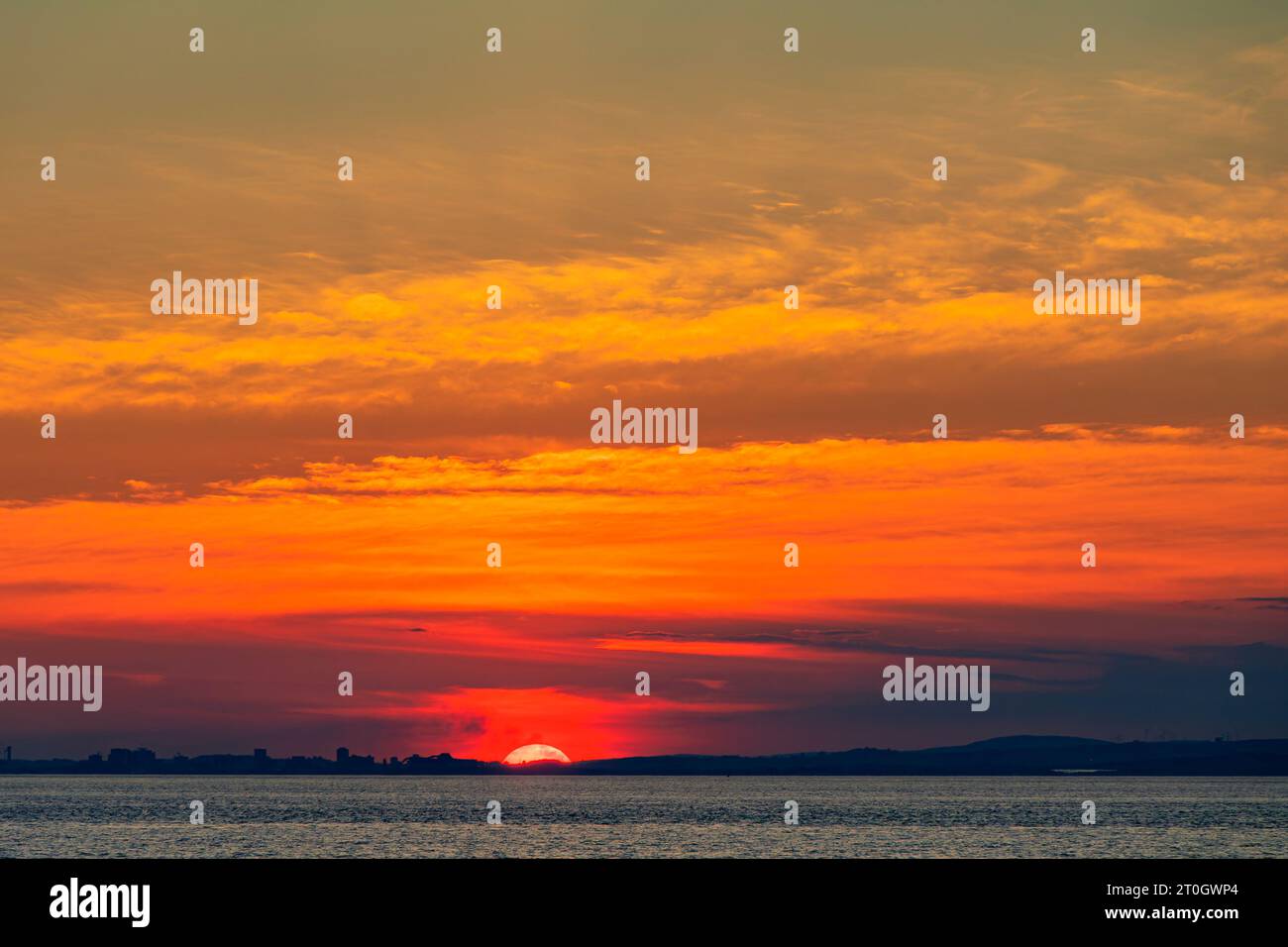 Il sole che tramonta illumina la nuvola lungo la costa gallese Foto Stock