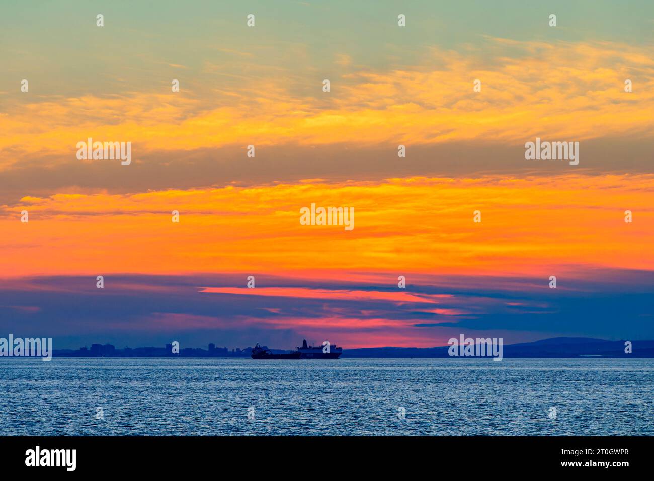 Il sole che tramonta illumina la nuvola lungo la costa gallese Foto Stock