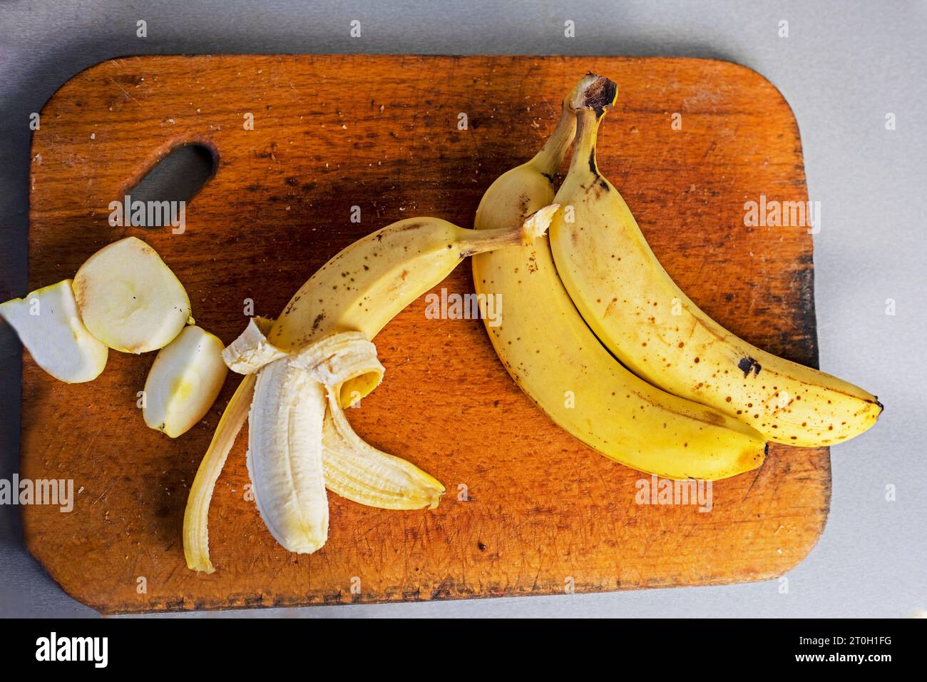 mazzo di banane con fette di mela su un tagliere di legno su sfondo grigio. flatlay Foto Stock