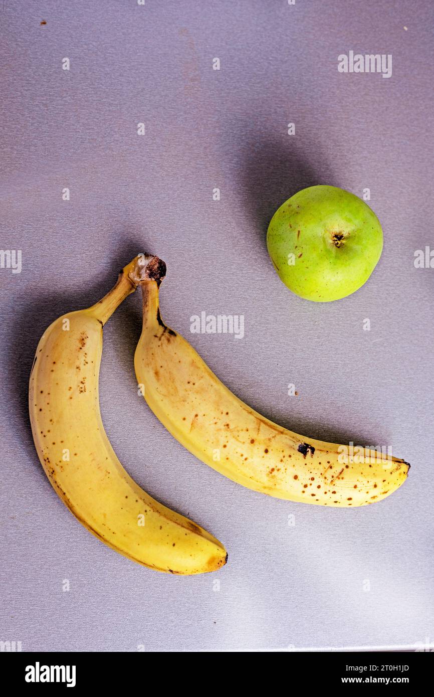 banane mature con mela verde su un tavolo grigio. flatlay Foto Stock