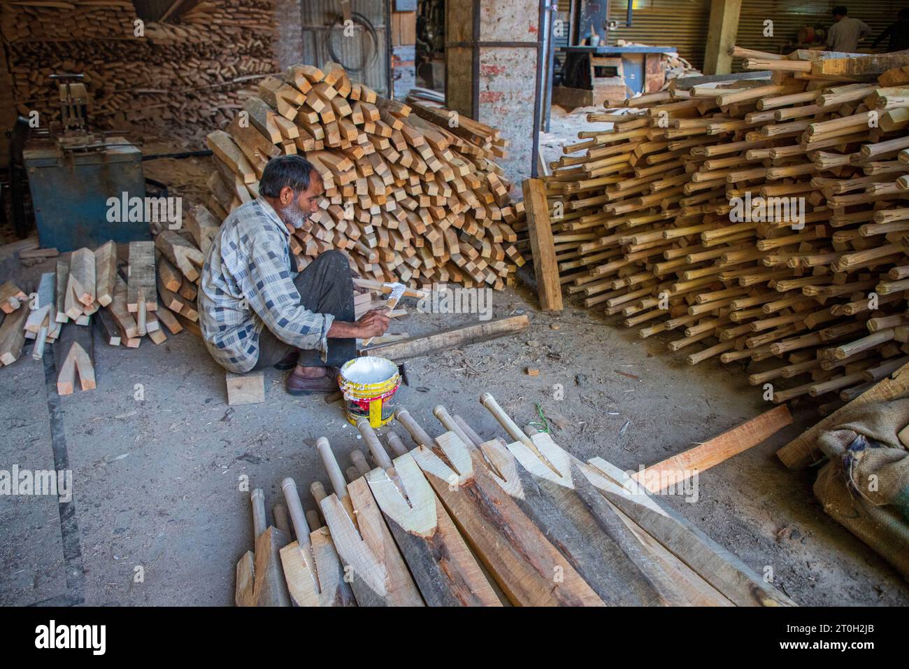 Un operaio incolla colla la colla sulla maniglia della mazza da cricket prima di fissarla alla mazza da cricket incompiuta fatta di legno di salice Kashmiri in una fabbrica a Sangam Anantnag, circa 50 km a sud di Srinagar. Per la prima volta nei 102 anni di produzione di pipistrelli nella valle, le mazze da cricket realizzate con il famoso salice del Kashmir saranno utilizzate da 17 giocatori internazionali di cricket nelle prossime partite di Coppa del mondo maschile (50-over) all'International Cricket Council (ICC), ospitato dall'India che inizia il 5 ottobre 2023. GR8 SPORTS, un'azienda produttrice di mazze in Kashmir, fornirà le mazze a squadre come Sri Lanka, Bangladesh, e. Foto Stock