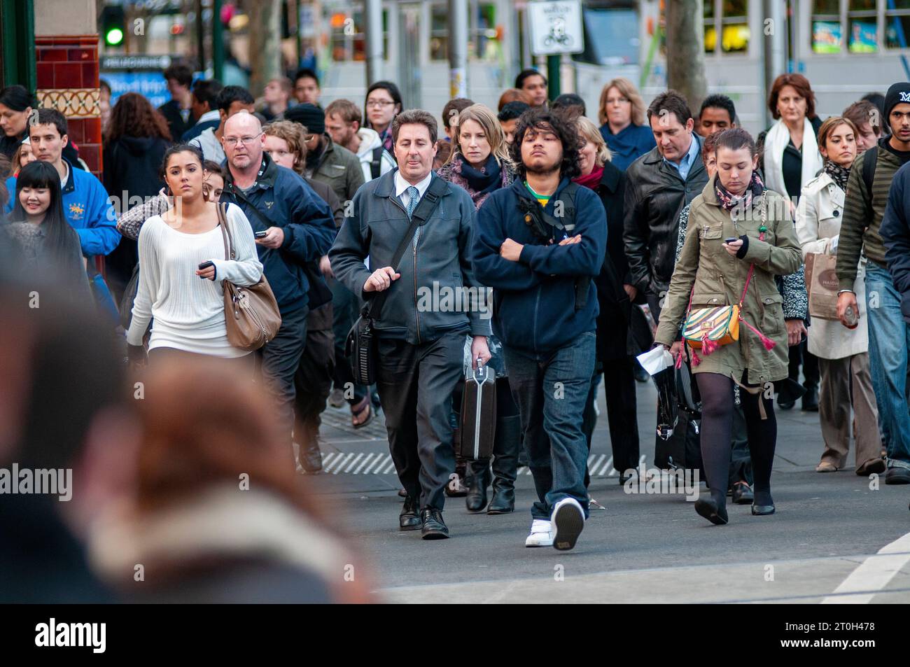 Pendolari diretti a casa all'attraversamento pedonale fuori dalla stazione di Flinders Street a Melbourne, Australia Foto Stock