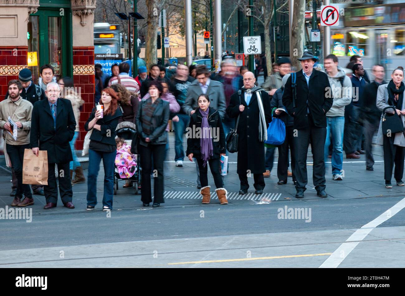 Pendolari diretti a casa all'attraversamento pedonale fuori dalla stazione di Flinders Street a Melbourne, Australia Foto Stock