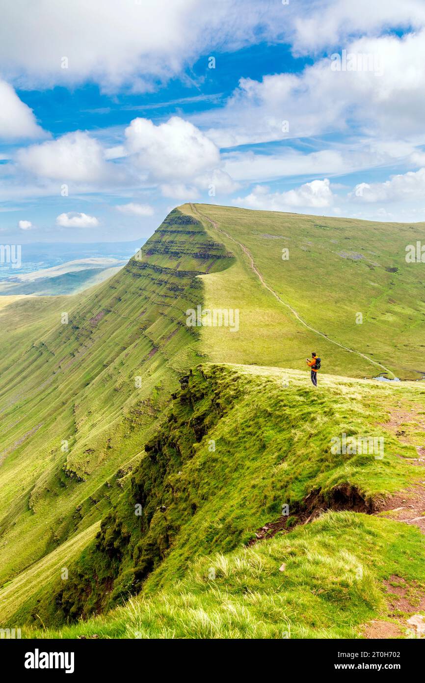 Escursionista che scatta foto con la cima del Cribyn sullo sfondo, il Brecon Beacons National Park, Galles, Regno Unito Foto Stock