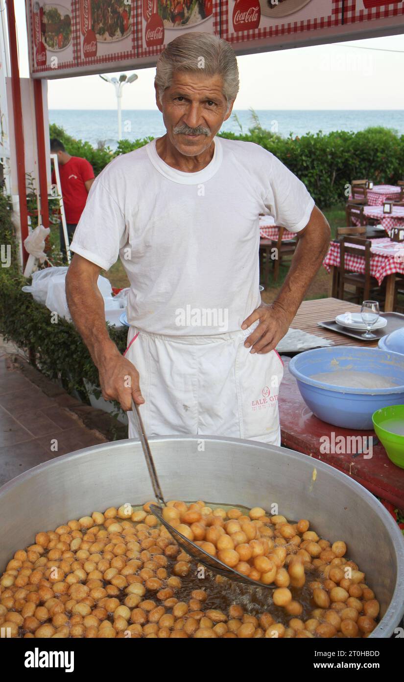 MERSIN, TURCHIA-AGOSTO 05: Chef non identificato che frigge il tradizionale dessert turco Lokma, detto anche Donut Holes. Agosto 05,2012 a Mersin, Turchia Foto Stock