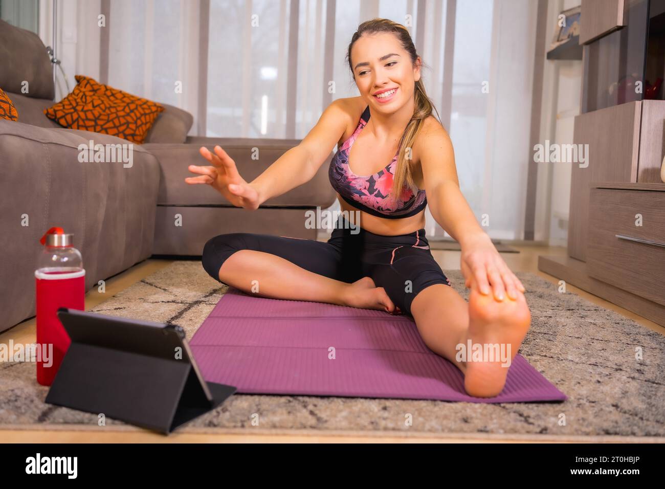 Fare esercizio a casa con in una classe online, caucasico fare esercizi di yoga e salutare il monitor sul tablet Foto Stock