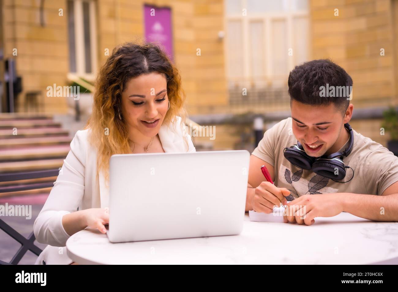 Giovani imprenditori che fanno lavoro di squadra. Lavorare su Internet con il computer sulla terrazza di un bar Foto Stock