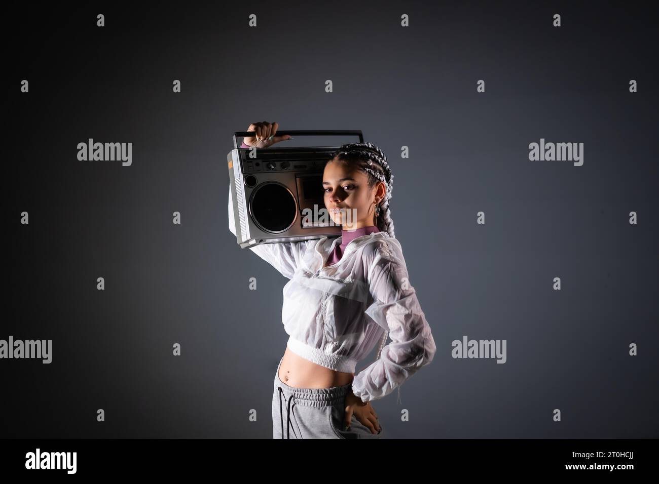 Ritratto di una giovane ragazza con trecce bianche con boombox vintage, sfondo nero, stile 80s, fotografia retrò Foto Stock