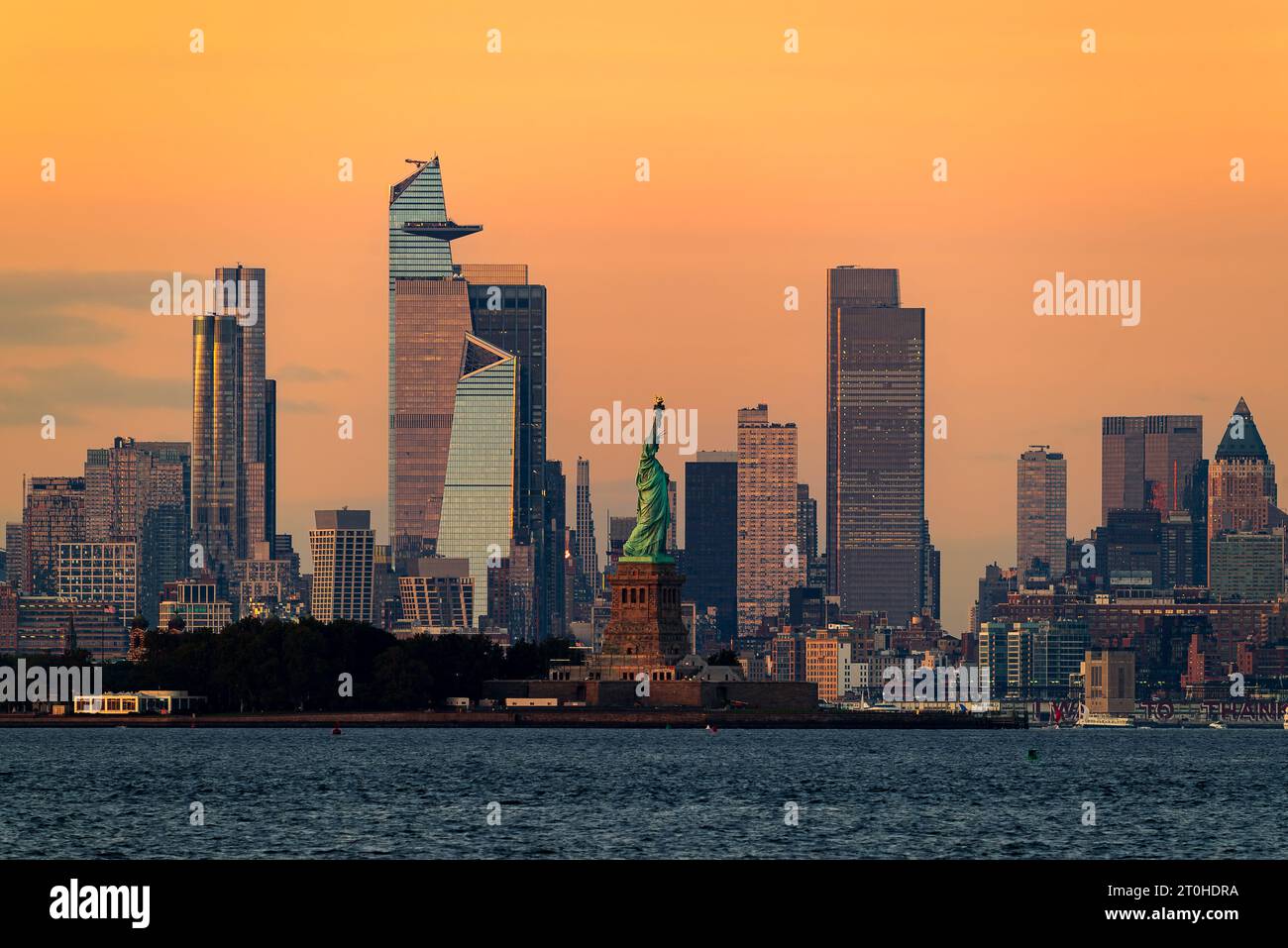 Paesaggio urbano in Gold Hour a New York. Inclusa la Statua della libertà. Lady Liberty e' al centro dei grattacieli di New York e' sul backgrou Foto Stock