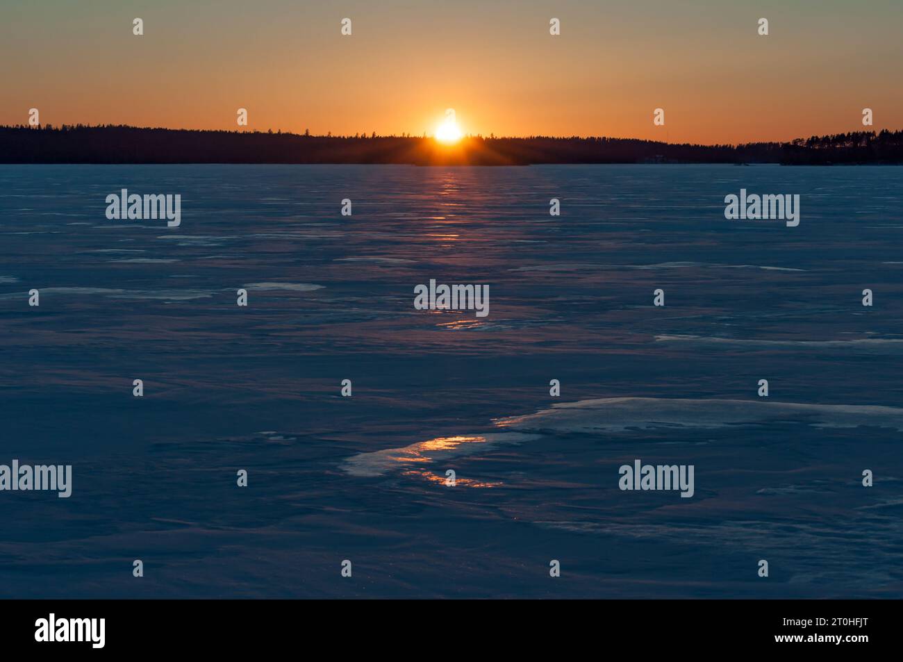 Tramontare il sole sul lago ghiacciato Päijänne in inverno in Finlandia Foto Stock