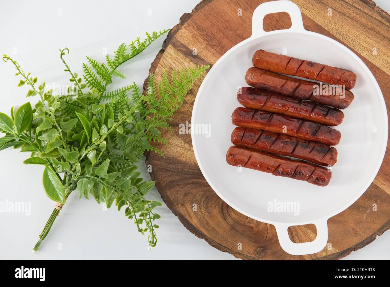 Vista dall'alto delle salsicce fritte e grigliate con salsa in un piatto bianco e fondo isolato. Salsicce di pollo speziate fritte nell'olio. Foto Stock