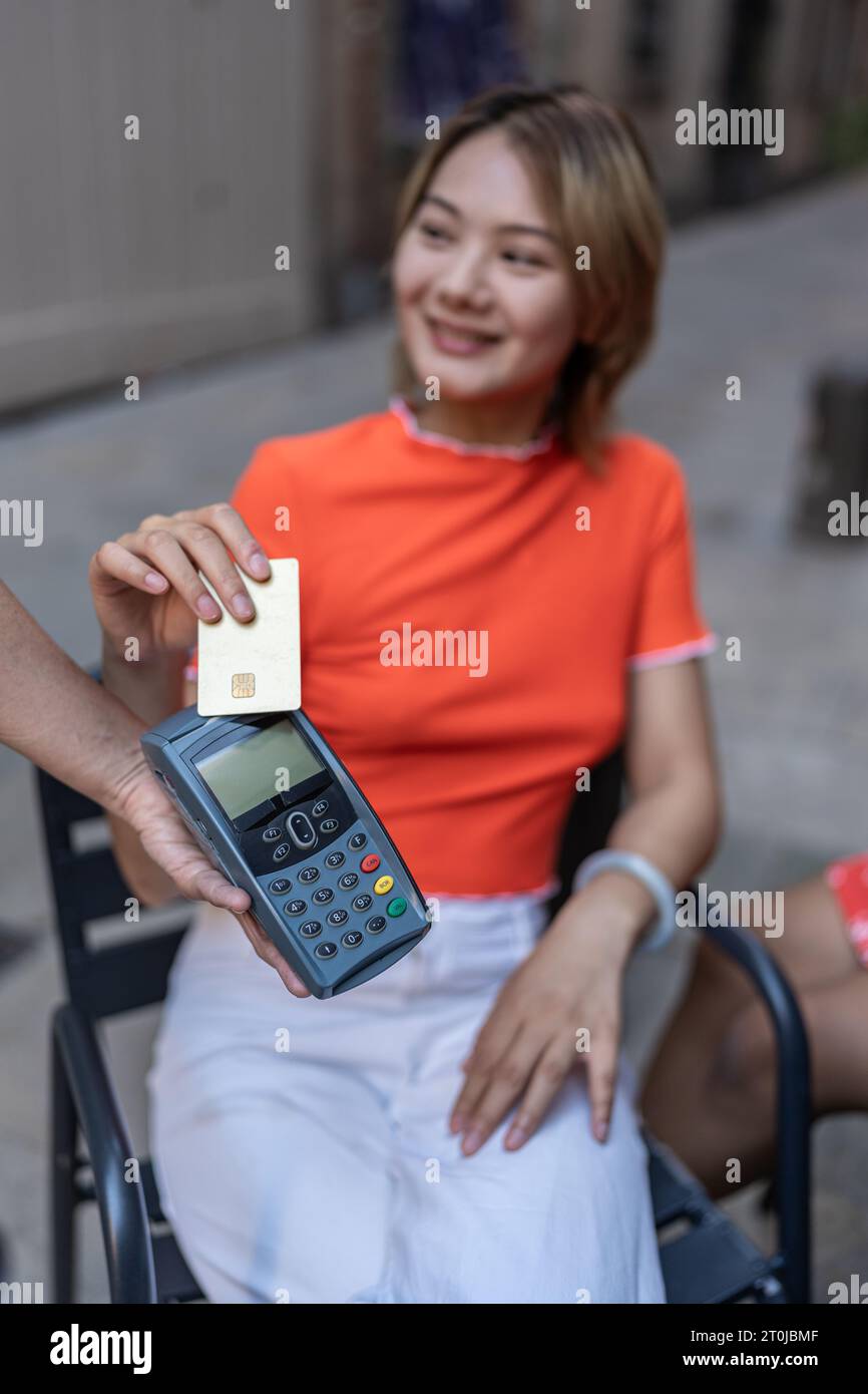 Donna cinese che paga con carta di credito seduta in terrazza Foto Stock