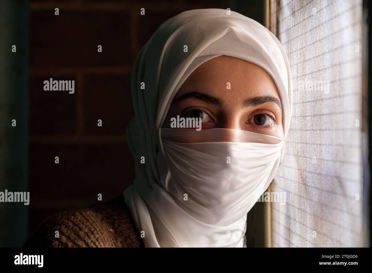 Donna musulmana che indossa una maschera e prega allah per proteggerla dalle malattie Foto Stock