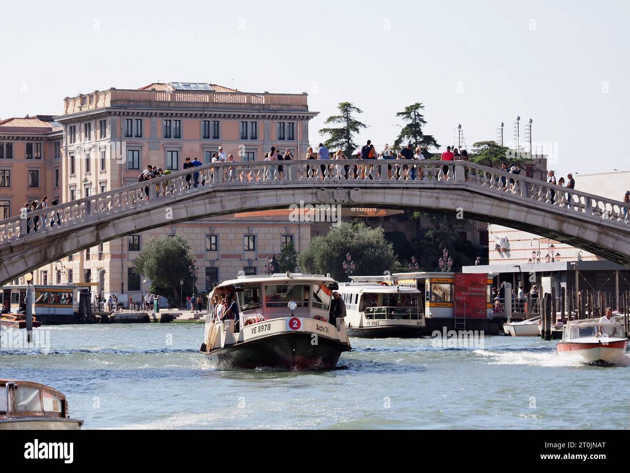 Scene di Venezia, Italia il 6 ottobre 2023. I turisti attraversano un ponte mentre un vaporetto, noto anche come vaporetto, passa sotto il Canal grande. Foto Stock