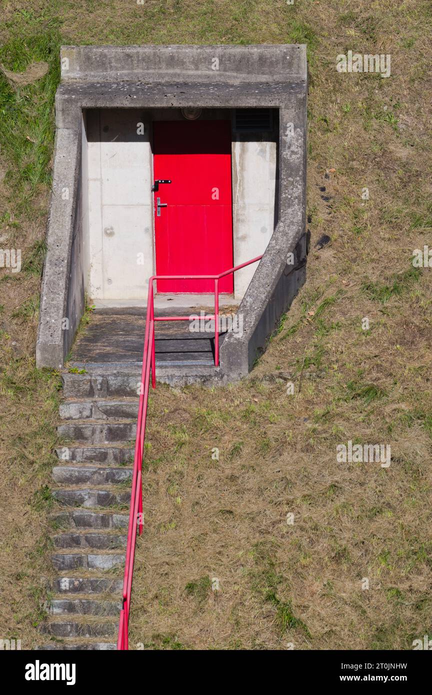 Porta misteriosa rossa che conduce al sottosuolo sulla collina sotto la diga del serbatoio d'acqua. Foto Stock