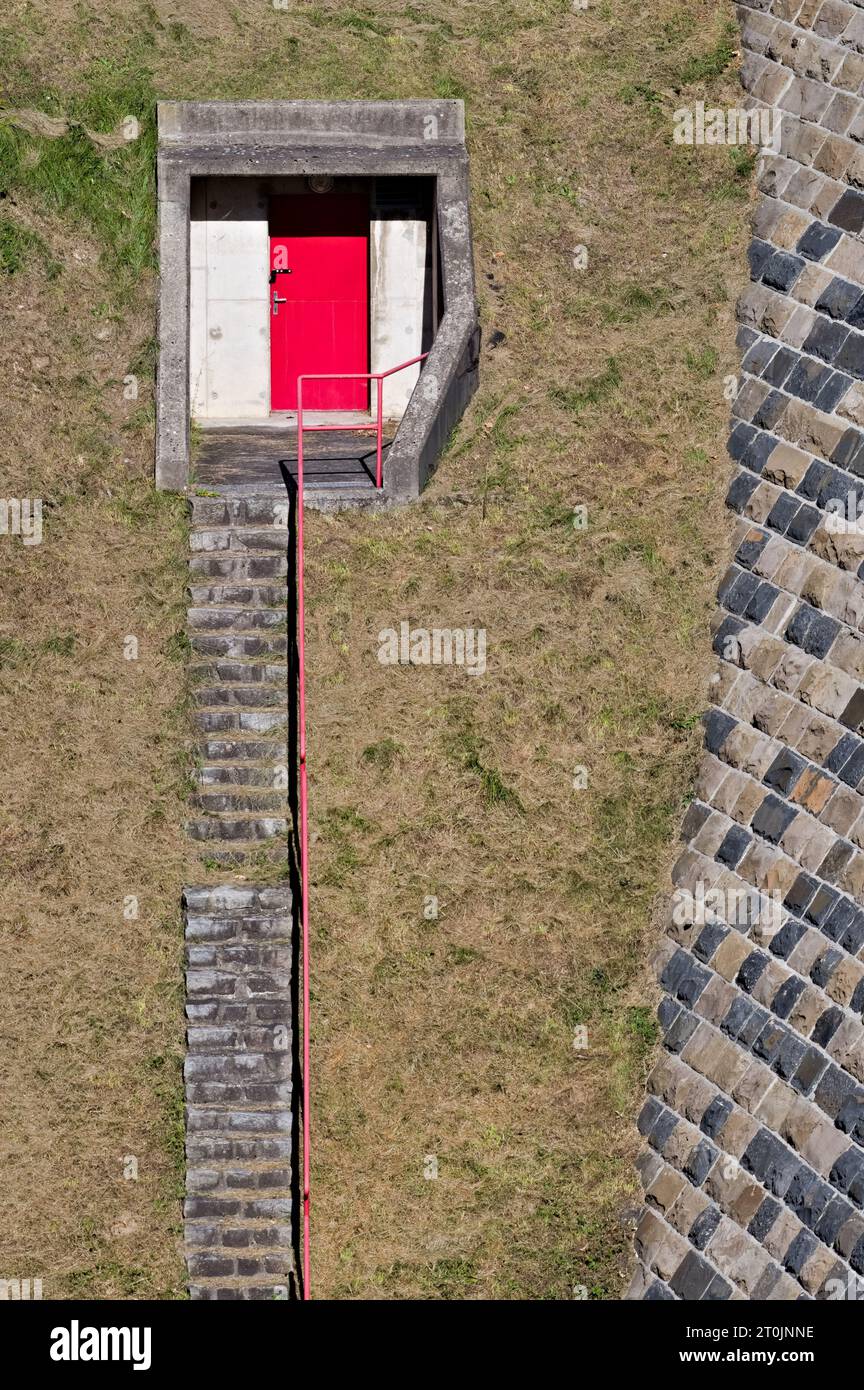 Porta misteriosa rossa che conduce al sottosuolo sulla collina sotto la diga del serbatoio d'acqua. Foto Stock