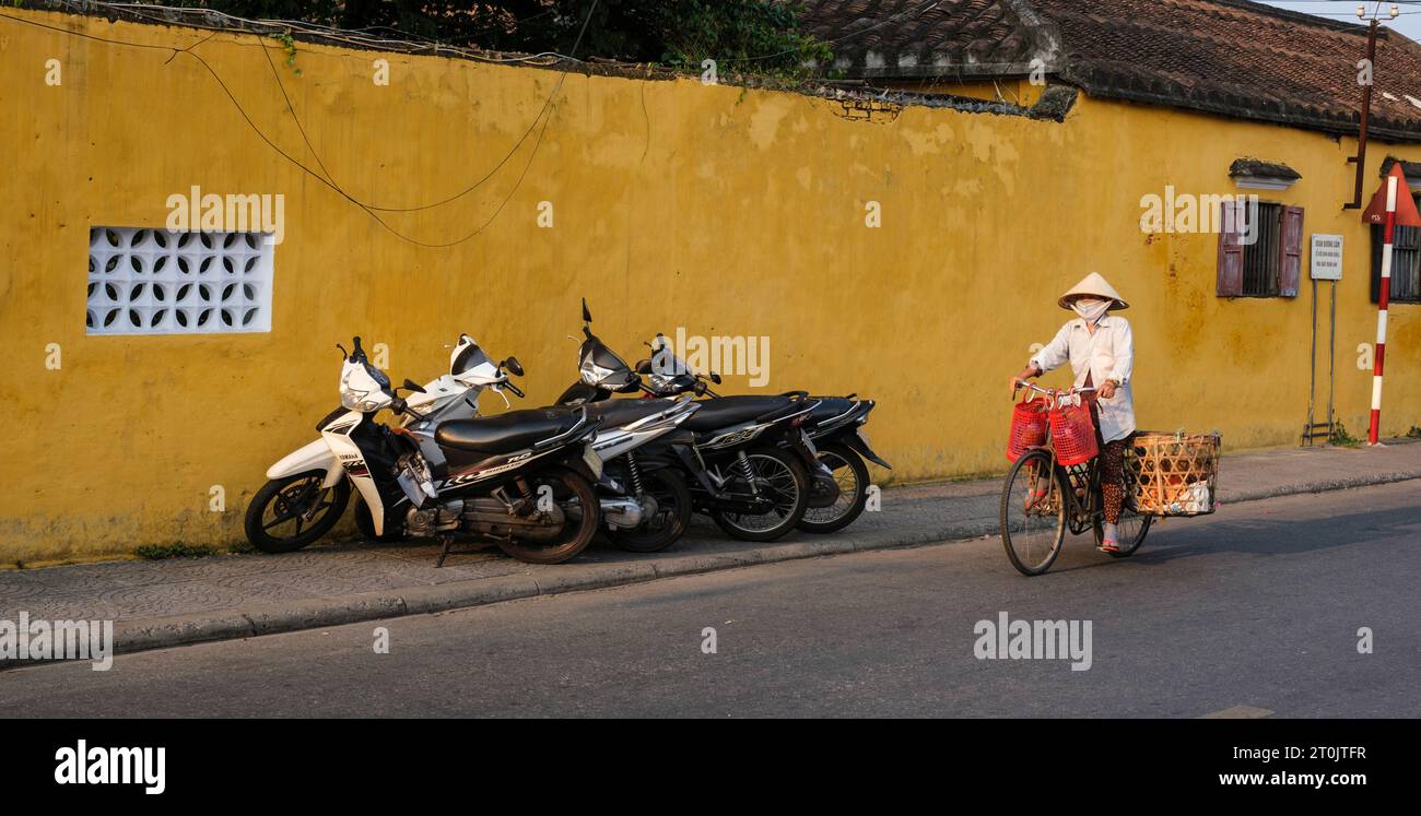 Hoi An, Vietnam. Donna di mezza età Riuding Bicycle. Foto Stock