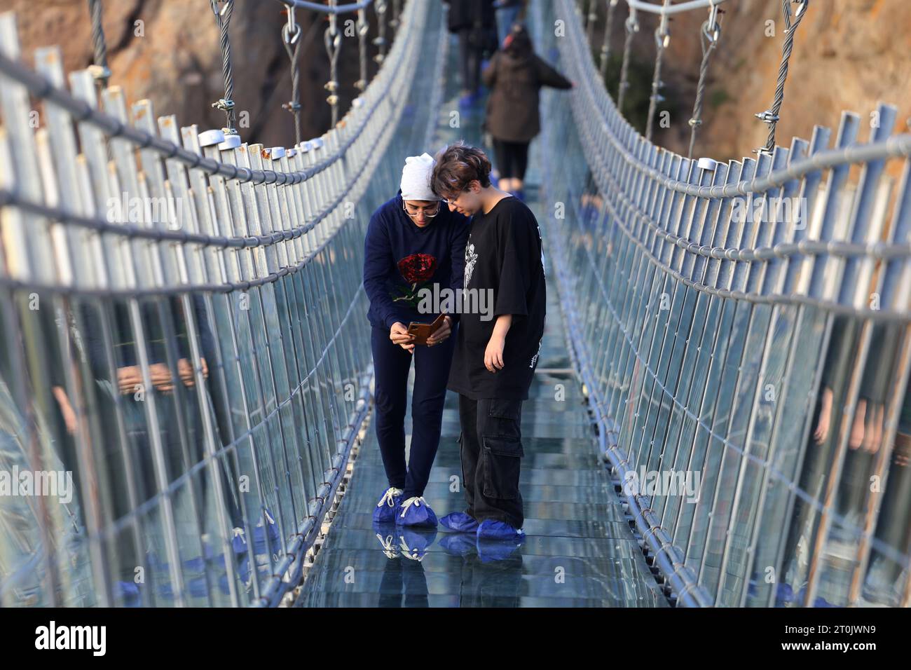 Hir, Ardabil, Iran. 5 ottobre 2023. Un'adolescente iraniana scatta una foto dal ponte sospeso in vetro ad arco nell'area ricreativa di Hir vicino alla città di Ardabil. Con i suoi 208 metri di lunghezza, 1,5 metri di larghezza e 100 metri di altezza, il ponte è un luogo frequentato dai turisti. (Immagine di credito: © Rouzbeh Fouladi/ZUMA Press Wire) SOLO USO EDITORIALE! Non per USO commerciale! Foto Stock