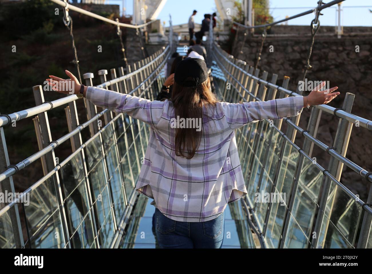 Hir, Ardabil, Iran. 5 ottobre 2023. Una donna iraniana senza coprire il suo velo islamico obbligatorio posa per una foto sul ponte sospeso in vetro ad arco nell'area ricreativa di Hir vicino alla città di Ardabil. Con i suoi 208 metri di lunghezza, 1,5 metri di larghezza e 100 metri di altezza, il ponte è un luogo frequentato dai turisti. (Immagine di credito: © Rouzbeh Fouladi/ZUMA Press Wire) SOLO USO EDITORIALE! Non per USO commerciale! Foto Stock
