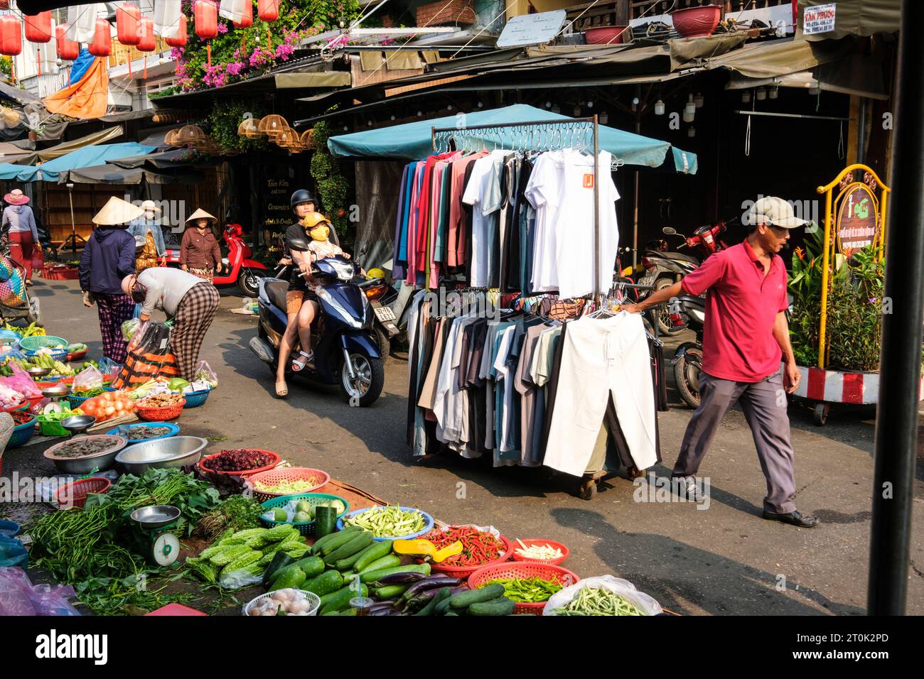 Hoi An, Vietnam. Fornitore di abbigliamento che cammina attraverso il mercato. Foto Stock