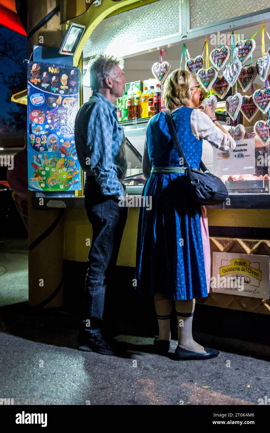 Donna in abito tradizionale che acquista dolci, il parco divertimenti Prater di notte, Vienna, Austria Foto Stock