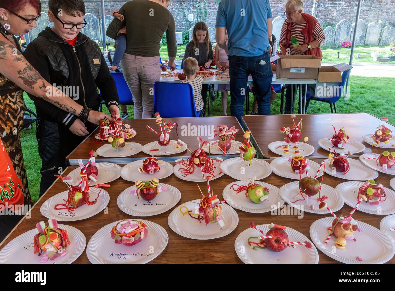 Bambini che decorano mele con caramelle o dolci in una divertente gara all'evento Alresford Apple Day, Hampshire, Inghilterra, Regno Unito, ottobre 2023 Foto Stock