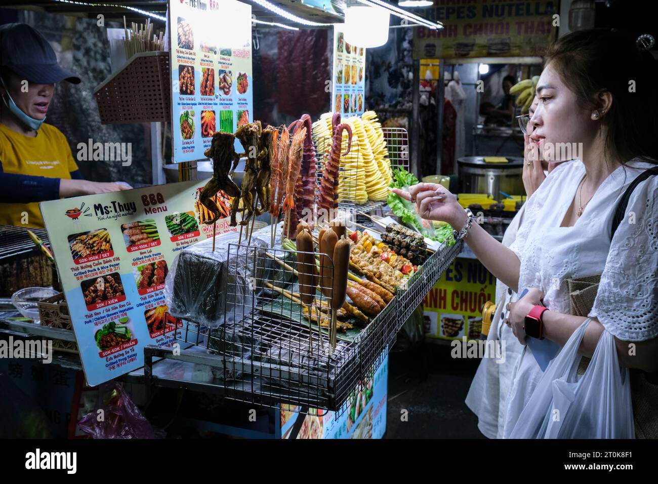 Hoi An, Vietnam. Fornitore e clienti di alimentari di strada al mercato notturno. Foto Stock