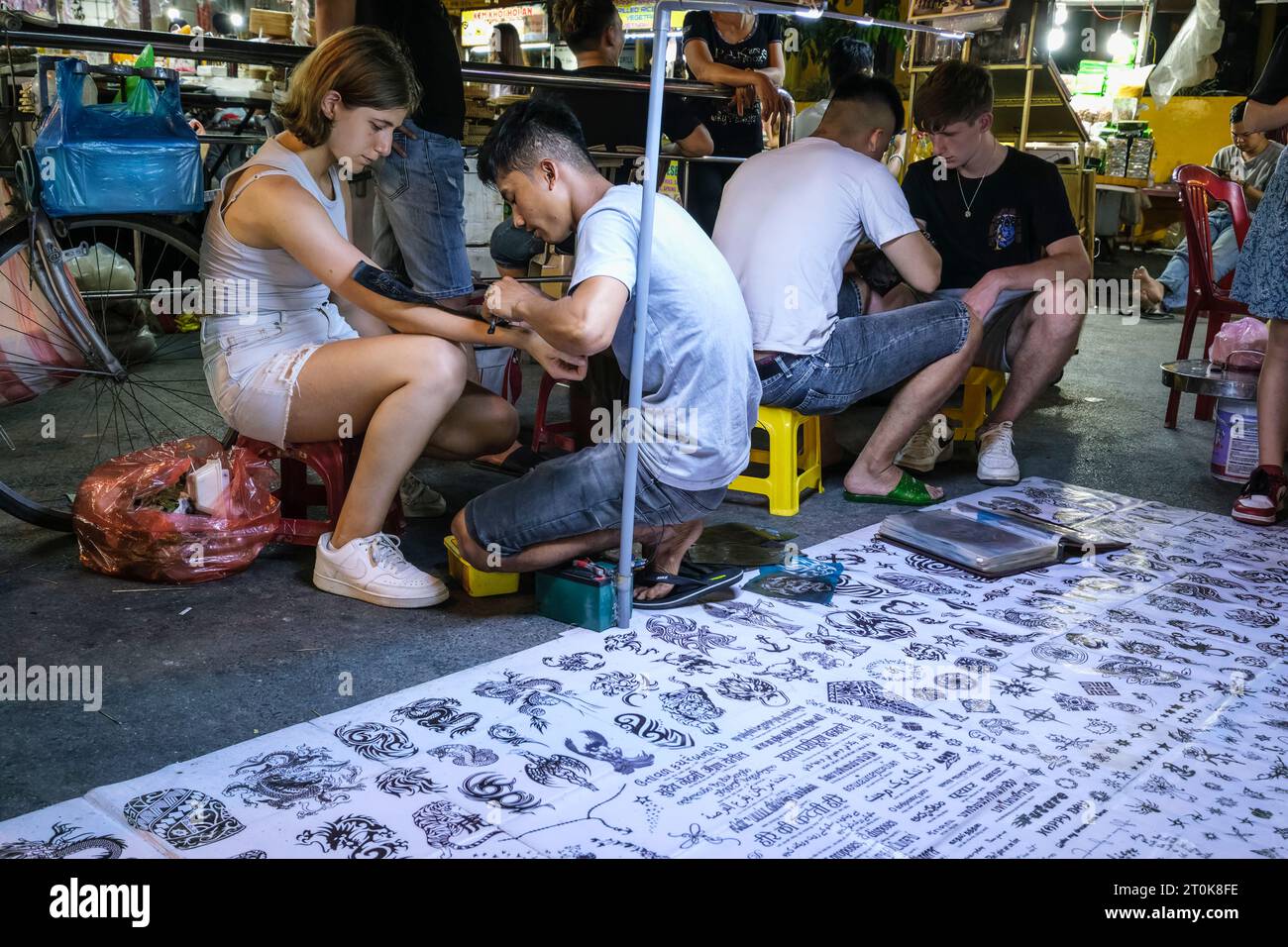 Hoi An, Vietnam. Cliente mercato notturno che ottiene tatuaggio. Foto Stock