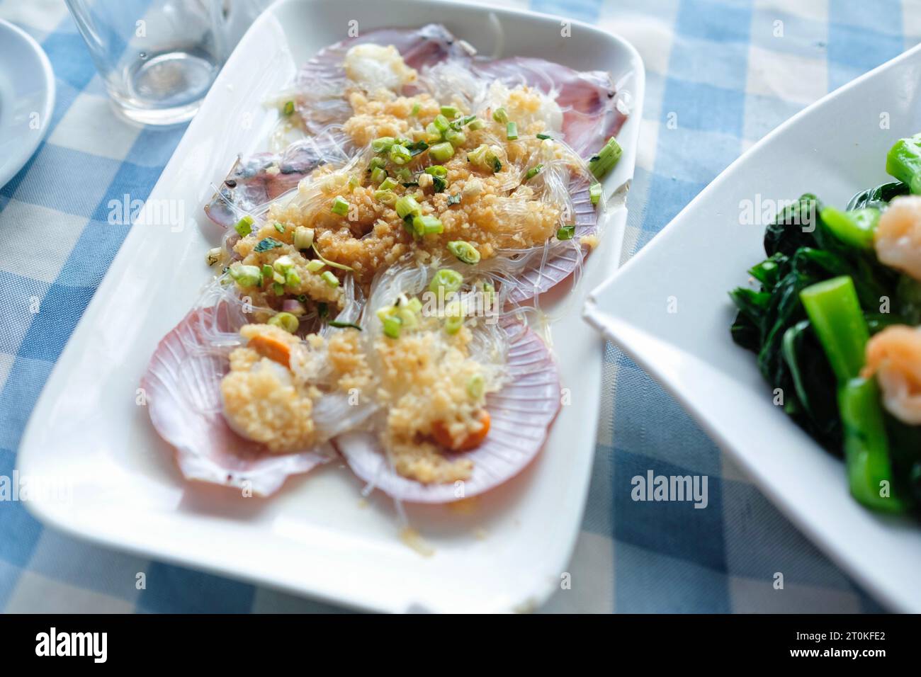 Capesante allo zenzero e scalogno con vermicelli e un piatto di verdure cinesi con gamberi all'aglio, in un ristorante di pesce sul mare lungo il molo di Cheung Chau Foto Stock
