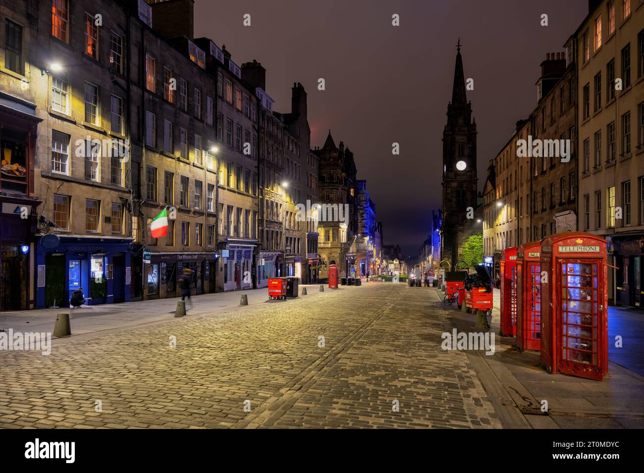 High Street nel Royal Mile di notte nella città vecchia di Edimburgo, in Scozia, Regno Unito. Iconiche cabine telefoniche rosse e torre Tron Kirk lungo cobb Foto Stock