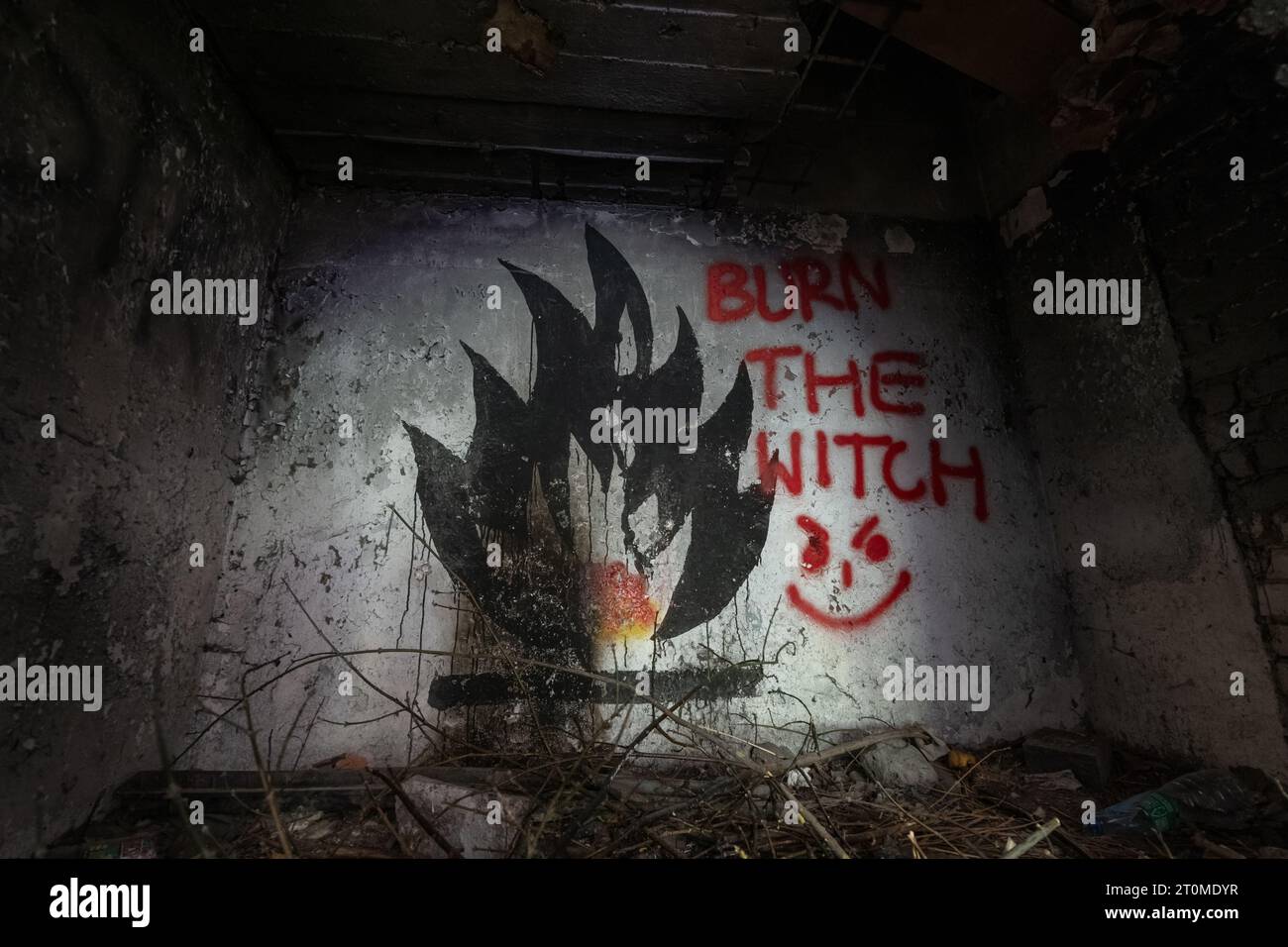 Camino inquietante con graffiti di fuoco e parole che bruciano la Strega in una spaventosa sala abbandonata. Foto Stock