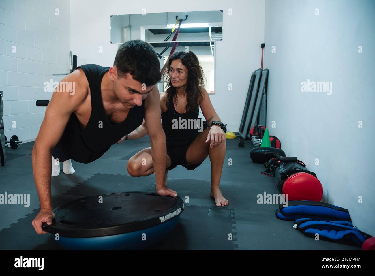 Il personal trainer assiste e dirige un giovane durante la sua sessione di allenamento in palestra. L'istruttore, un esperto di fitness, fornisce istruzioni precise Foto Stock