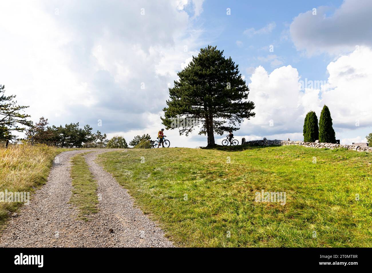 Madre e figlio in gita in bicicletta esplorando un sentiero remoto circondato da uno spettacolare paesaggio di scogliere e foreste, zona di Pivka, Notranjska, Slovenia Foto Stock