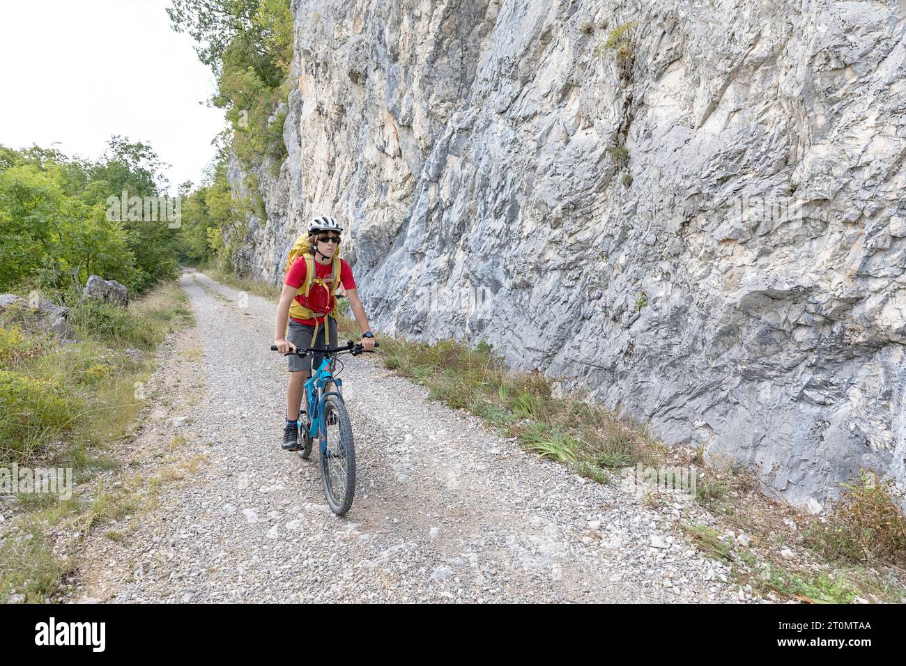 Ragazzo, turista in una gita in bicicletta nella campagna intorno a Pivka, pedalando su una vecchia strada militare italiana costruita prima della prima guerra mondiale, in slovenia Foto Stock