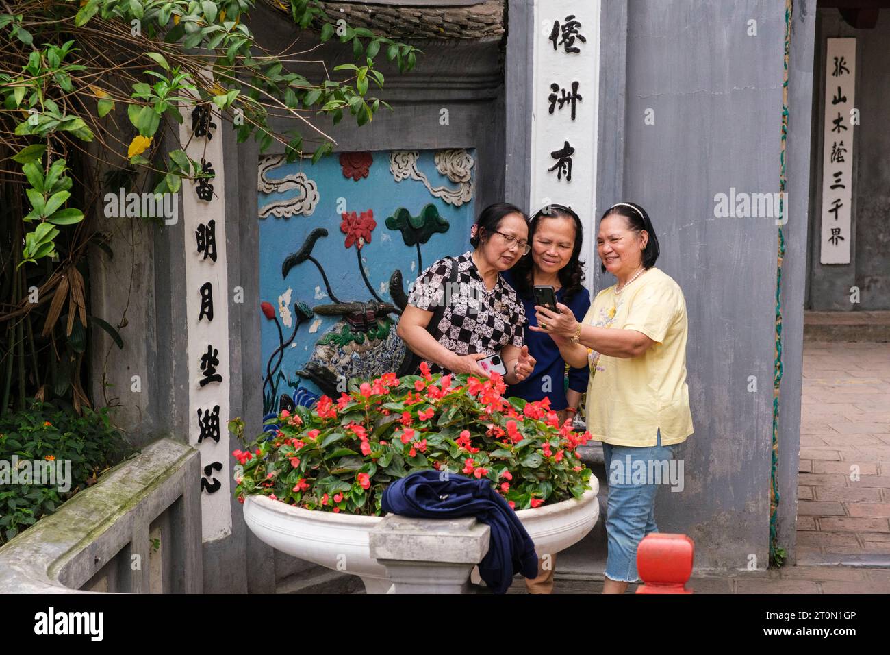 Hanoi, Vietnam. I turisti asiatici ispezionano foto all'ingresso del Tempio di Ngoc Son e del Tempio della montagna di Giada. Foto Stock