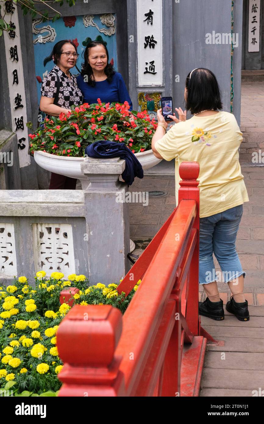 Hanoi, Vietnam. Il turista asiatico fotografa gli amici all'ingresso del Tempio di Ngoc Son e del Tempio della montagna di Giada. Foto Stock