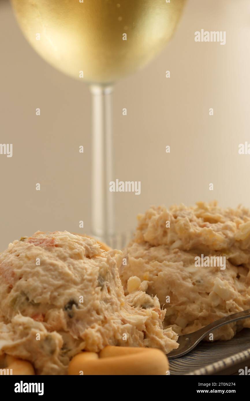 Antipasto con insalata russa con ciambelle di pane accompagnato da un bicchiere di vino bianco Foto Stock