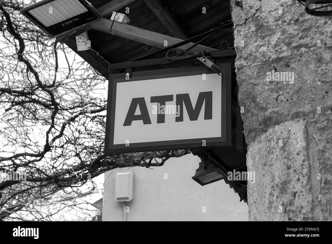 Un cartello bancomat appeso nella città vecchia di Rodi che informa di una macchina automatica per l'incasso nelle vicinanze in bianco e nero Foto Stock