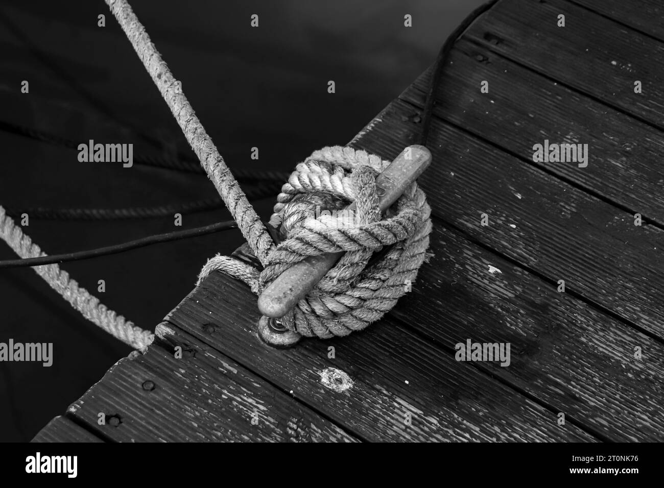 Paletto di ormeggio marino bianco e nero che fissa una barca a vela con corda in poliestere intrecciato Foto Stock