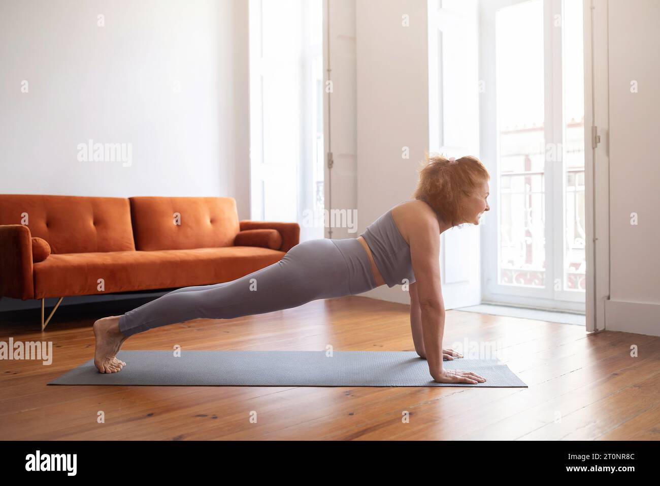 Sport nazionali. Donna anziana sorridente che fa esercizio Plank a casa Foto Stock