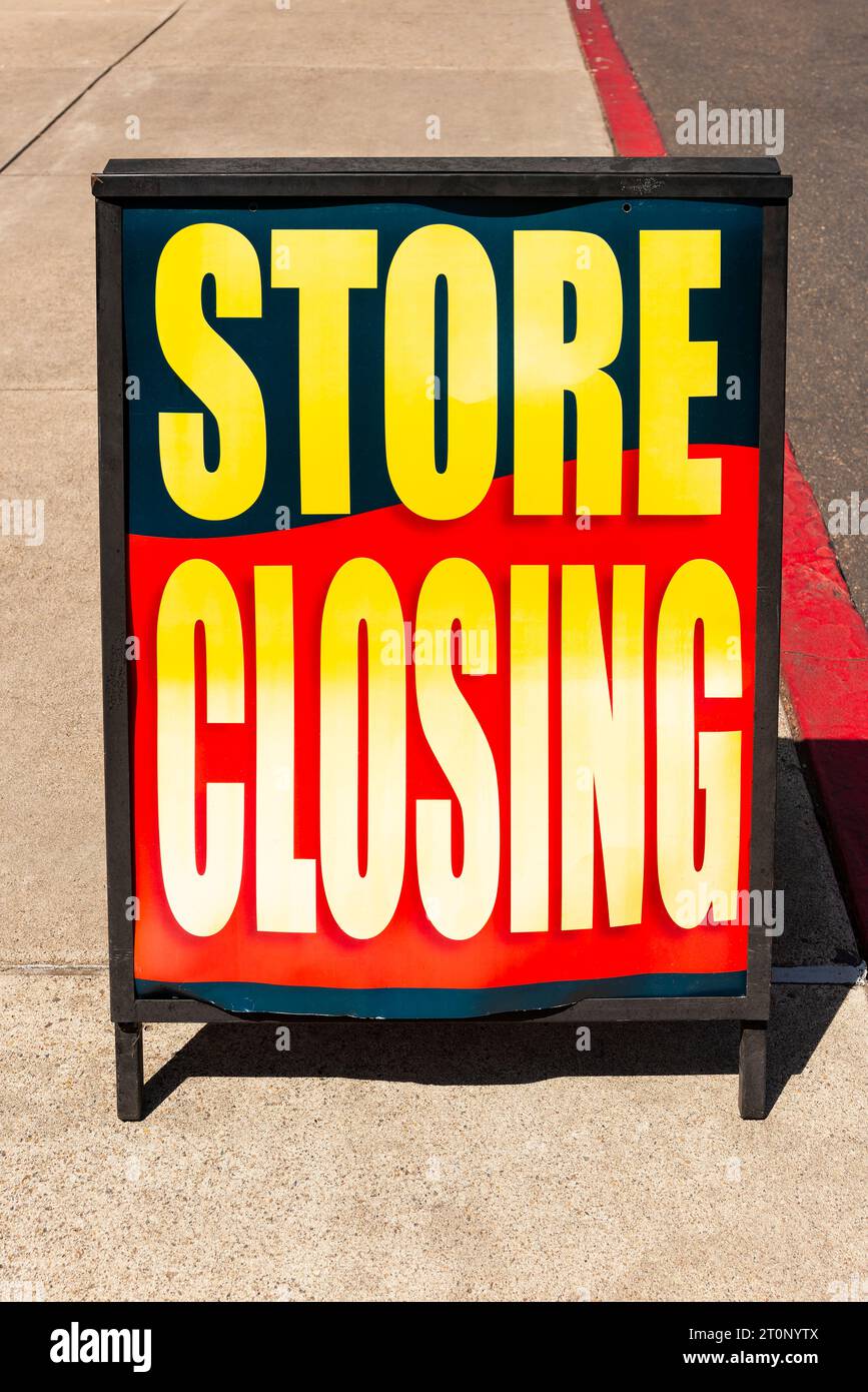 Cartello di chiusura del punto vendita sul marciapiede di fronte a un punto vendita che esce dall'attività. Foto Stock