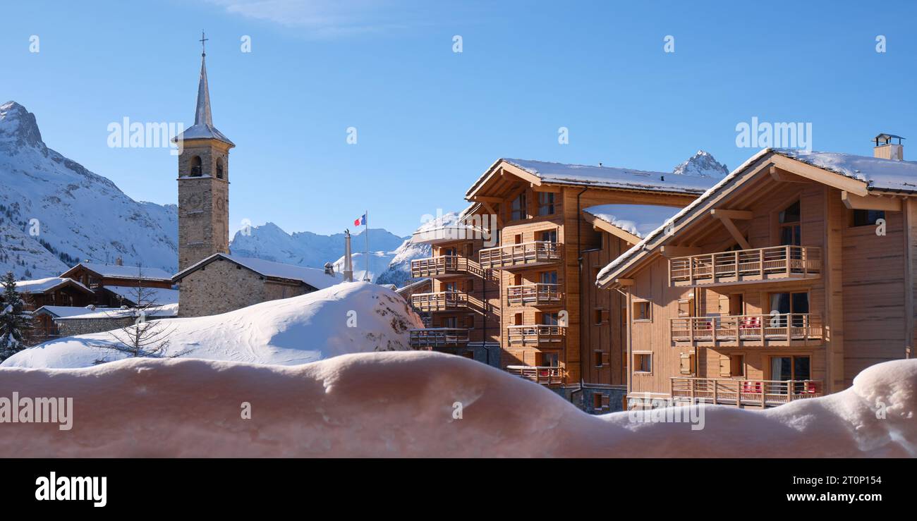 Chiesa e case di legno nella località sciistica di Tignes Village, Francia, in inverno, con un cielo azzurro. Turismo, sci, hotel, ski-in ski-out. Foto Stock