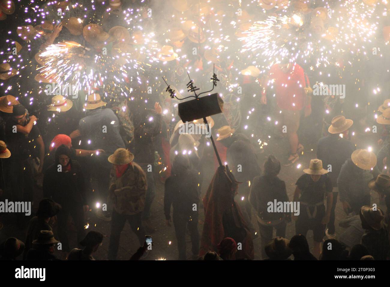 Persone che ballano sotto le docce di scintille dai fuochi d'artificio alle celebrazioni annuali di Santa Tecla a Tarragona al suono della batteria Foto Stock