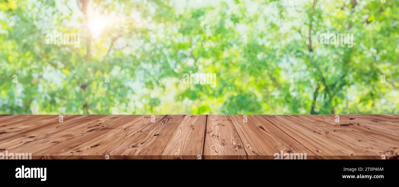 Bokeh verde sfocatura con tavolo in legno in primo piano per i prodotti Eco Natural pubblicità sfondo panoramico ampio Foto Stock