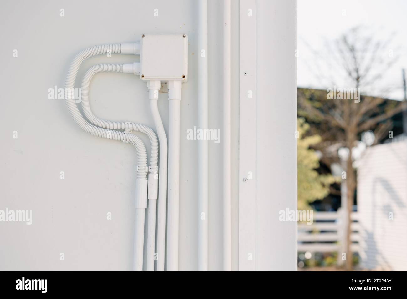 Installazione professionale a parete per cablaggio elettrico esterno con tubo protettivo in PVC e scatola connettore impermeabile. Foto Stock