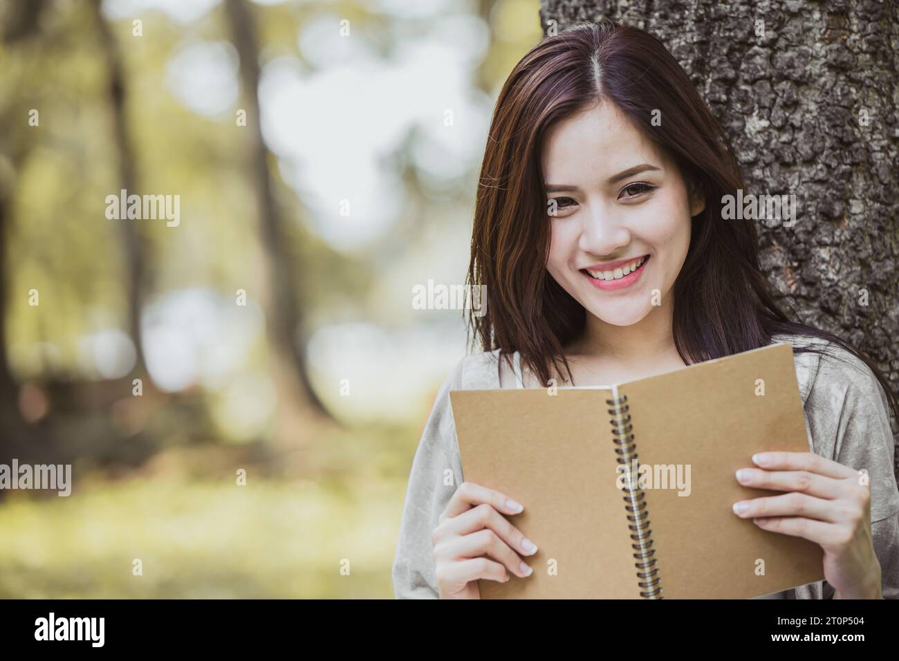 Bella, felice e sorridente donna asiatica con un libro, relax, lettura, apprendimento autonomo, intelligente parco verde all'aperto per adolescenti Foto Stock