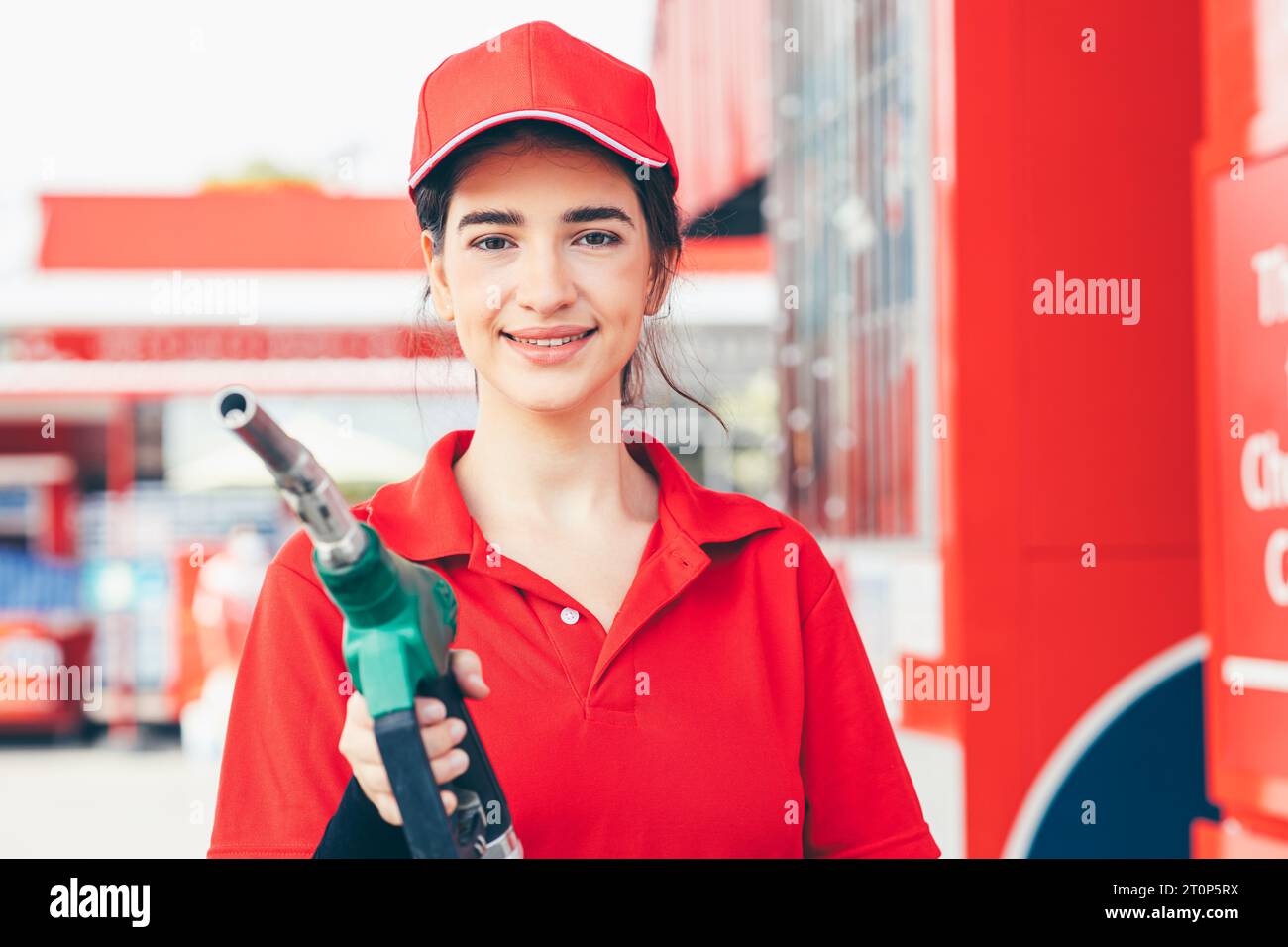 Le donne del personale addetto alla manutenzione delle stazioni di servizio sono felici di sorridere con la pistola erogatrice per il rifornimento di benzina per auto Foto Stock